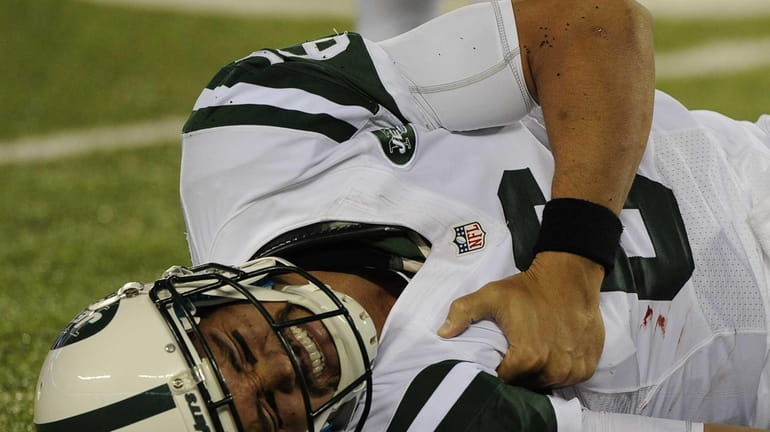 Jets quarterback Mark Sanchez winces in pain after going down...