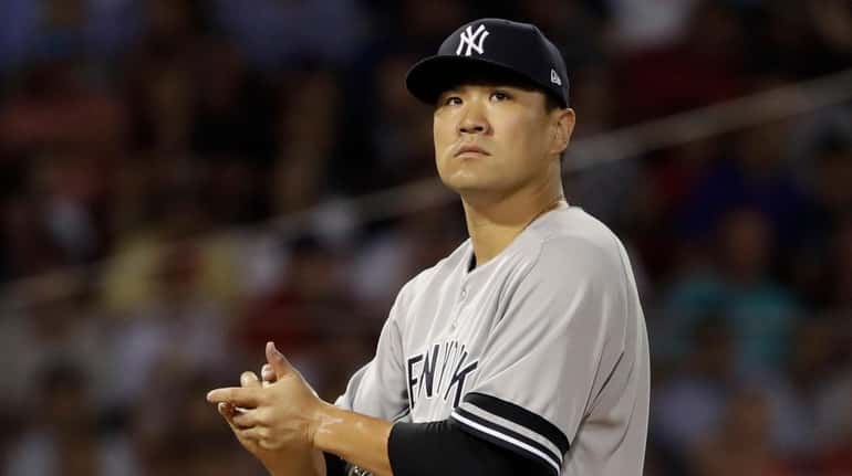 Yankees pitcher Masahiro Tanaka rubs the ball before he is...