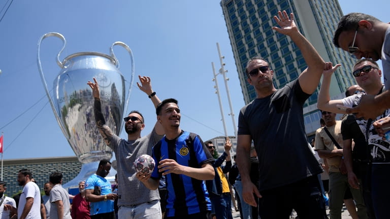 Soccer fans gather near a giant Champions League trophy shaped...