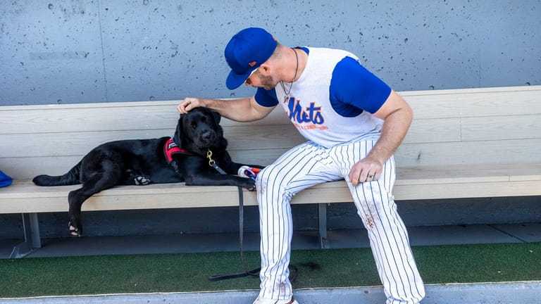 Mets first baseman Pete Alonso plays with Bear, a black...