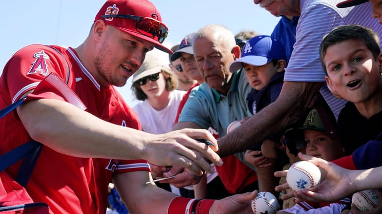 Los Angeles Angels' Mike Trout signs autographs for fans prior...