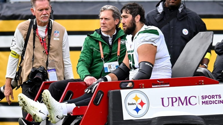 Max Mitchell of the Jets is carted off the field after being...