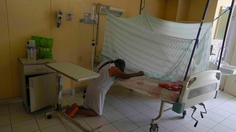 Ana Pasapera, who suffers from dengue, prays beside her bed...