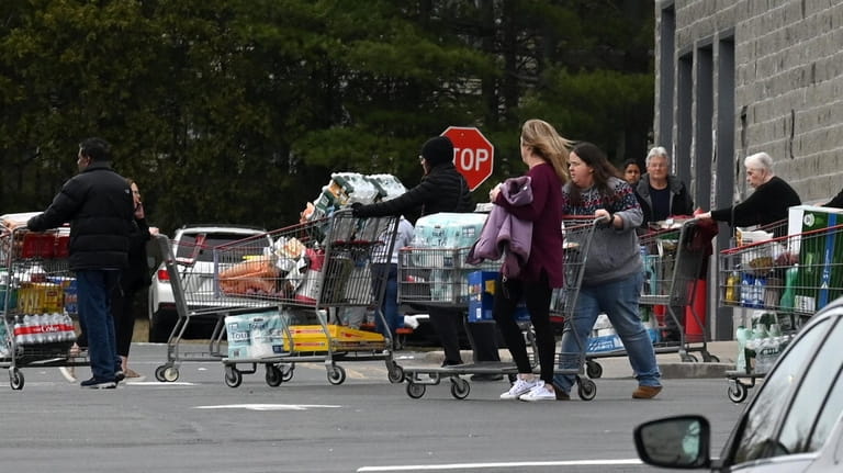 Shoppers make their way through the Costco parking lot with...