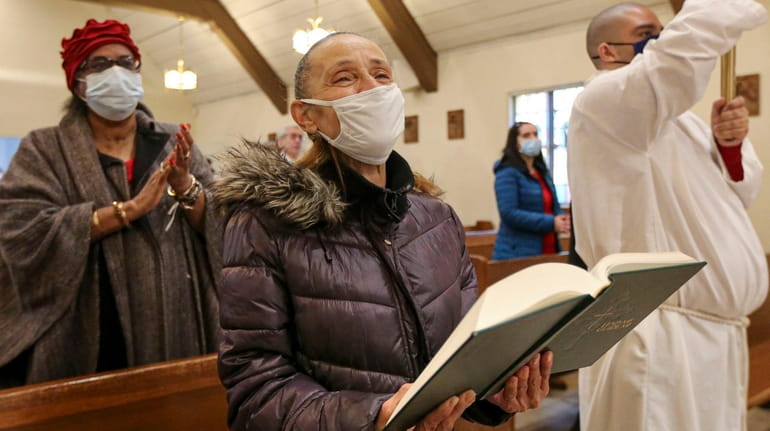 Wearing masks and social distancing, parishioners take part in the Mass...