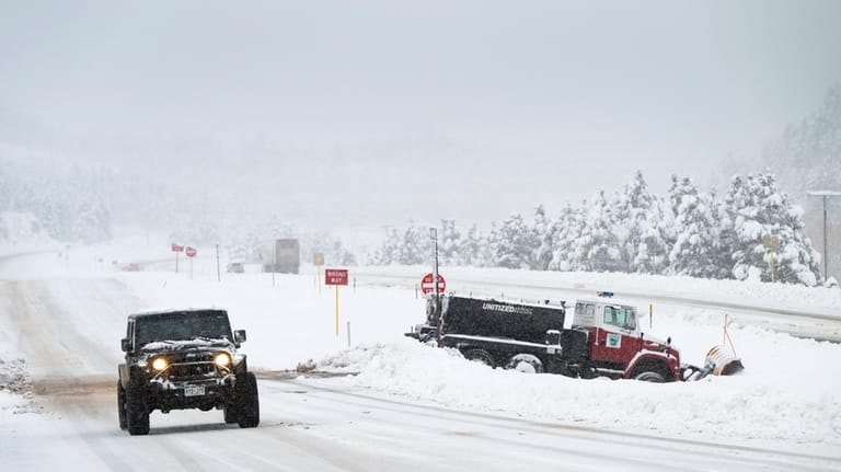 A jeep passes a stranded snowplow while traveling west of...