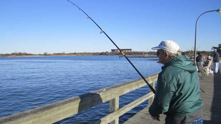 A fisherman waits for a bite by a bluefish or...