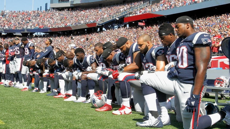 Members of the New England Patriots kneel during the national...