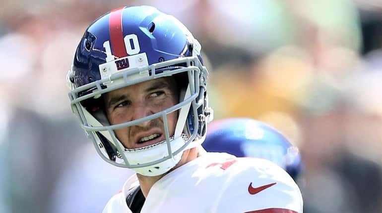 Eli Manning walks off the field after the Giants failed...