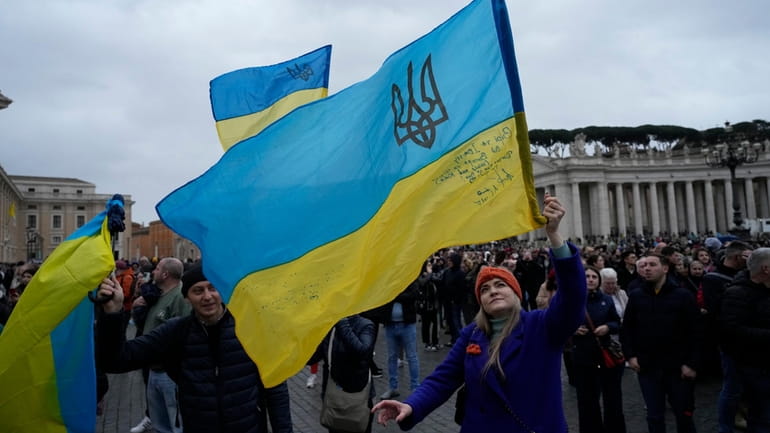 People wave Ukrainian flags before Pope Francis' noon prayer from the window...