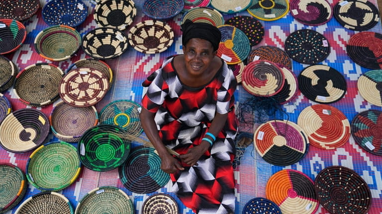 Anasitasia Nyirabashyitsi, 54, weaves a grass and thread bowl outside...