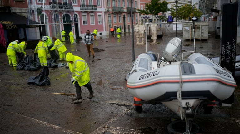 Municipal workers clean a street that was flooded overnight in...