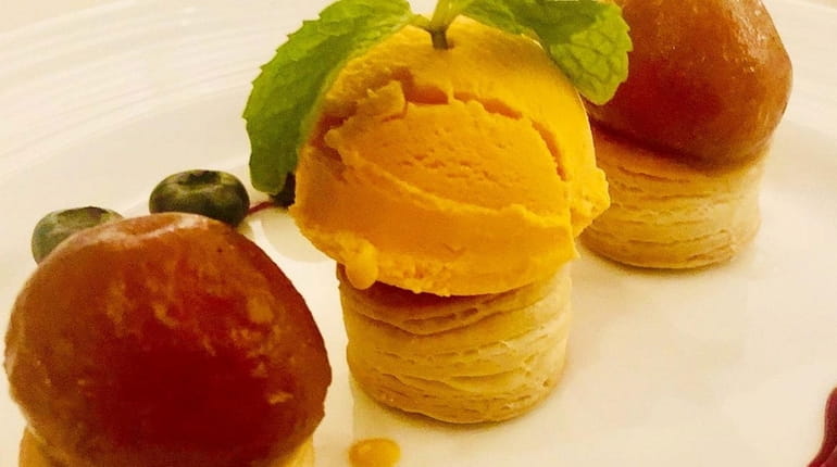 House-made mango ice cream flanked by glistening orbs of gulab...