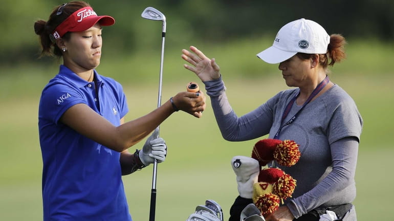 Annie Park takes a club from her caddie and mother,...