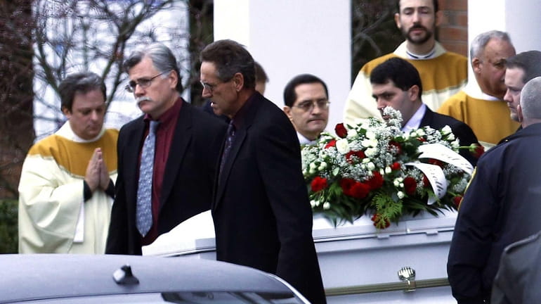 Pallbearers carry a casket out of St. Rose of Lima...