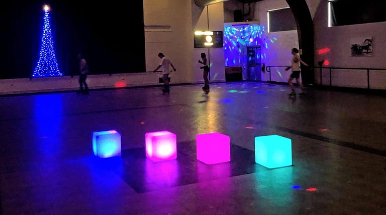 Roller skaters move under the disco ball while wheeling around...