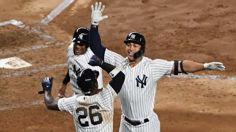 Yankees DH Giancarlo Stanton celebrates his grand slam with Aaron Hicks and...