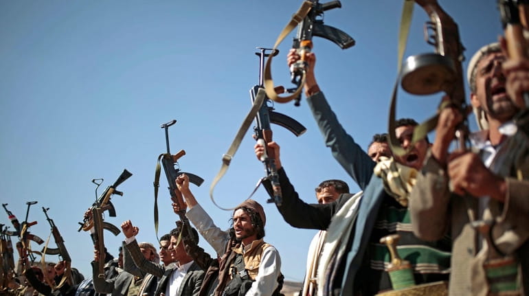 Tribesmen loyal to Houthi rebels hold up their weapons as...
