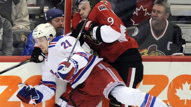 Ottawa Senators' Milan Michalek, right, is hit into the boards...