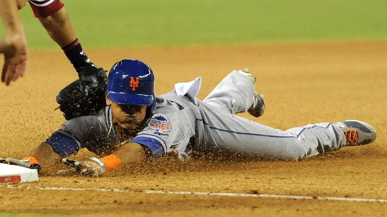 Juan Lagares #12 of the New York Mets slides safely...