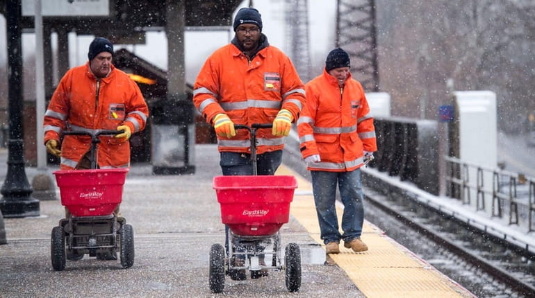LIRR employees spread salt at the Baldwin station in preparation...