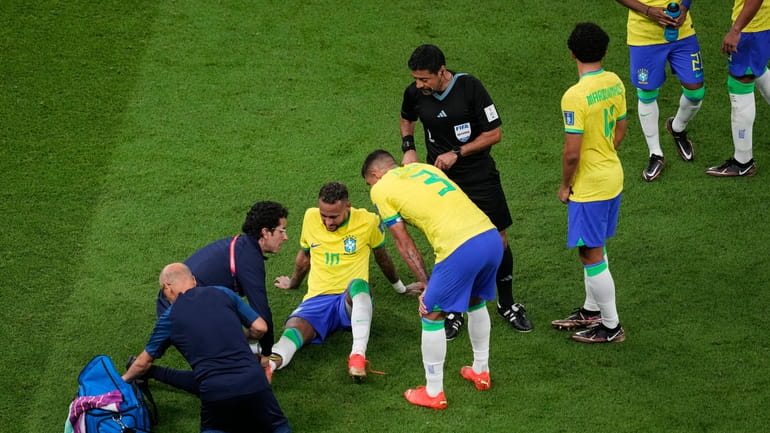 Brazil's Neymar, lies on the pitch as he receives first...