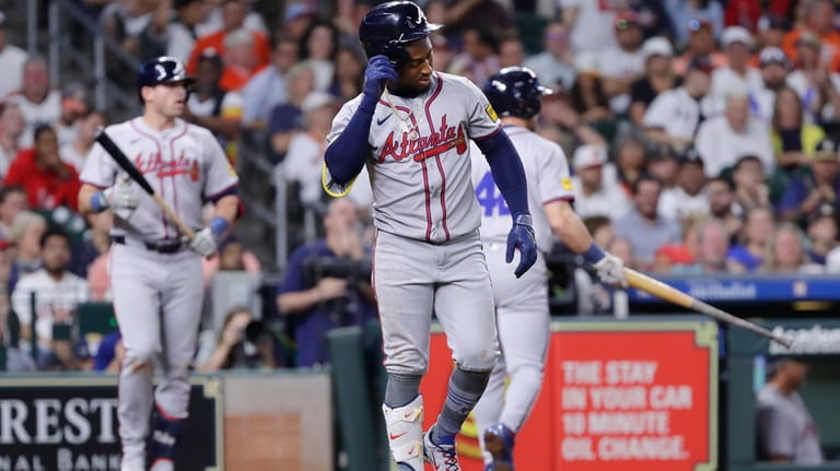 Atlanta Braves' Ozzie Albies limps to first base after getting...
