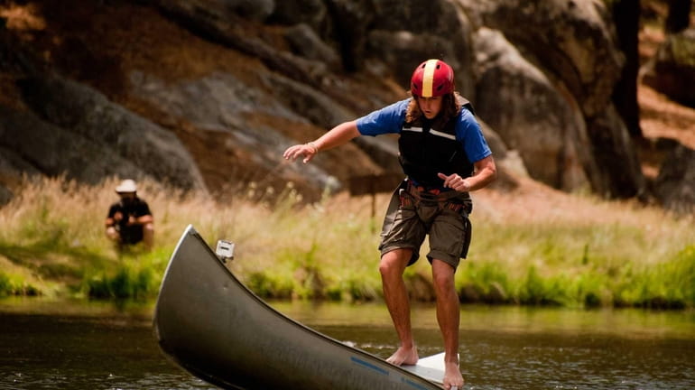 Keegan Rice stands on end of canoe in Kernville, Calif....
