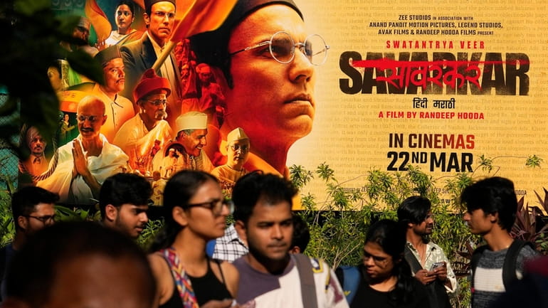 People walk past a large poster of the movie Swatantra...