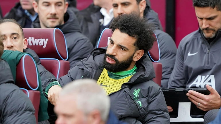 Liverpool's Mohamed Salah sits on the substitute bench ahead of...