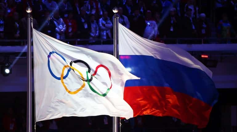The Olympic flag (L) and the Russian flag (R) during...
