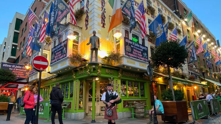 A bagpiper plays in front of the Oliver St. John...