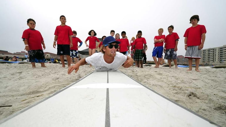 Surfing instructor Will Skudin shows young students how to pop...