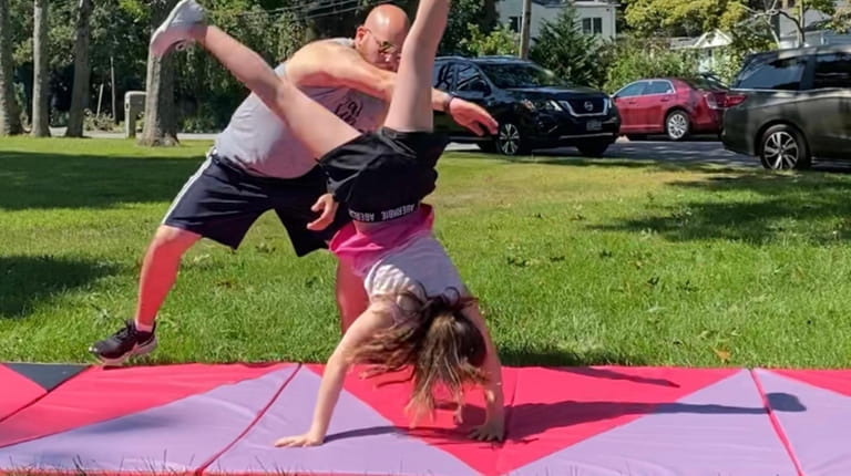 Caroline Fusco, 9, of Hauppauge, gets an at-home gymnastics lesson...