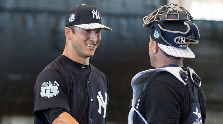 Yankees' pitcher James Kaprielian shakes hands with the bullpen catcher...