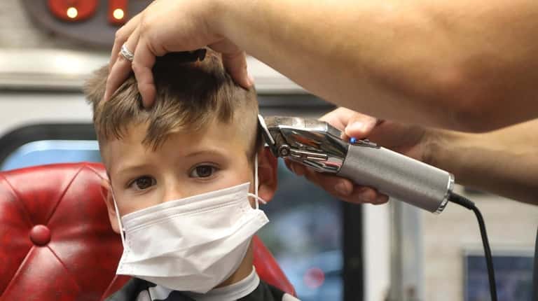 Jaxson Ronan, 6, gets his hair cut from barber Mike...