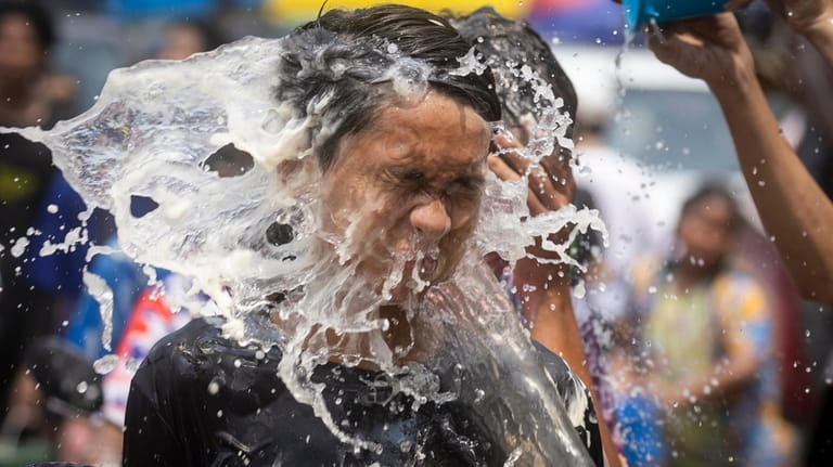 A man reacts as water is splashed on him during...