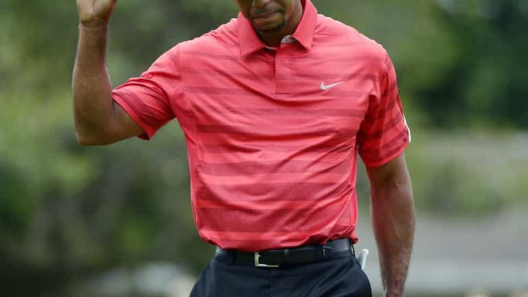 Tiger Woods acknowledges the crowd after sinking his putt for...