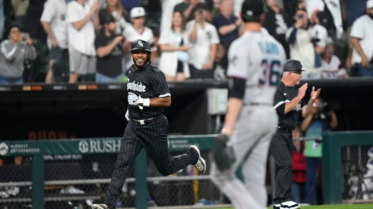 Chicago White Sox's Elvis Andrus smiles as he scores on...