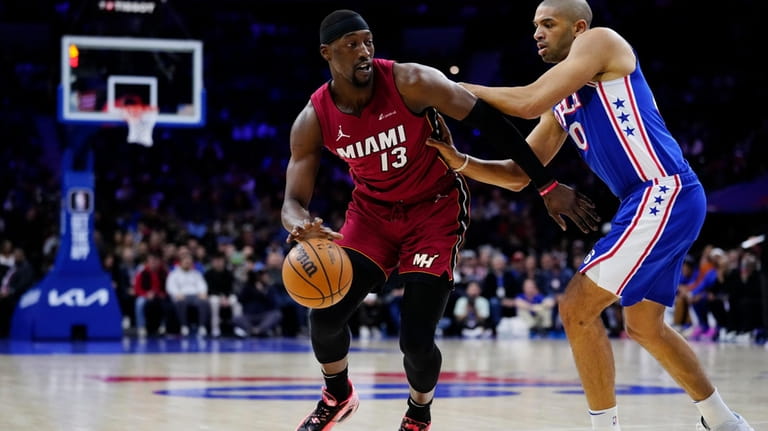 Miami Heat's Bam Adebayo, left, tries to get past Philadelphia...