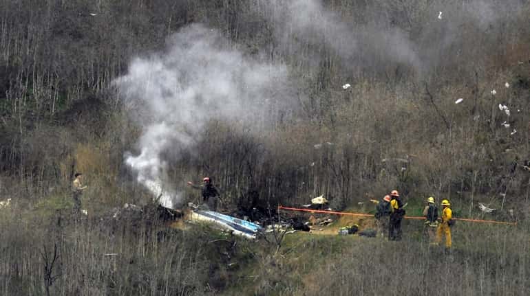 Firefighters work the scene of a helicopter crash Sunday, Jan....