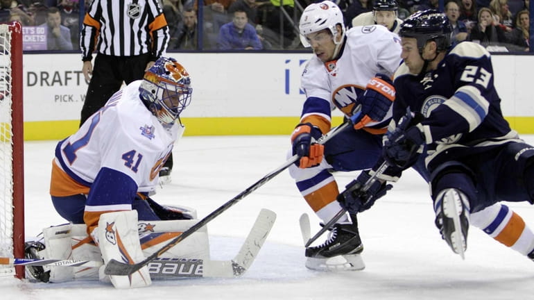 New York Islanders' Jaroslav Halak, left, makes a save as...