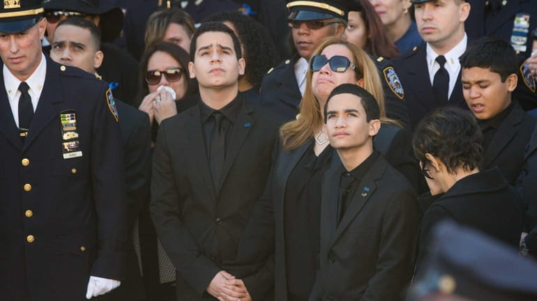 Officer Rafael Ramos' wife Maritza is flanked by sons Justin...