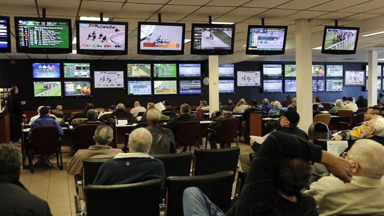 Players watch the first race at Aqueduct at Nassau OTB...