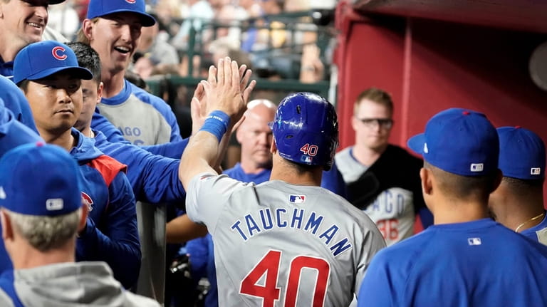 Chicago Cubs' Mike Tauchman (40) gets high-fives from teammates after...