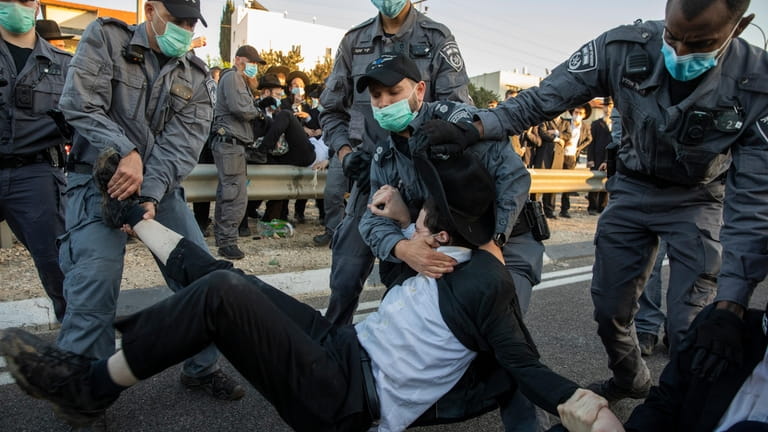 Israeli police try to clear ultra-Orthodox Jews blocking a highway...