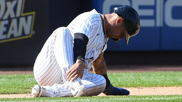 The Yankees' Gleyber Torres sits on the ground after he...