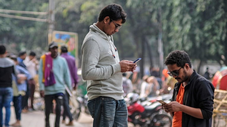 People engage with their mobile phones at Dhaka University area,...