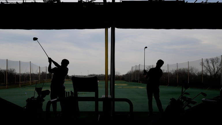 Golfers hit range balls during a warm day in Des...