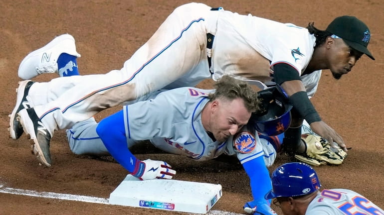 The Mets' Brandon Nimmo, bottom left, collides with Marlins third...